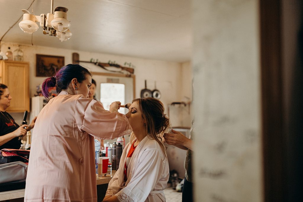 Bride getting ready with makeup artist doing makeup