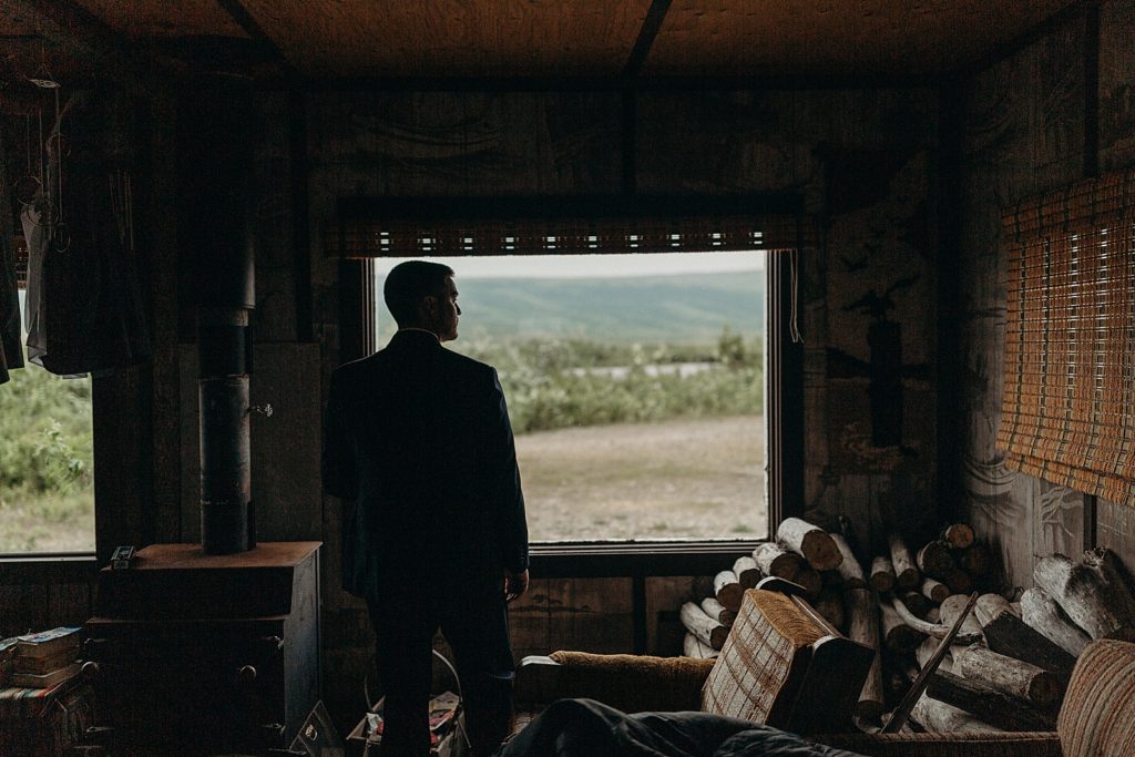 Groom in dark room looking outside