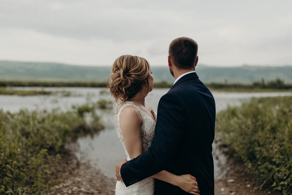 Bride and Groom looking at the lake hugging each other