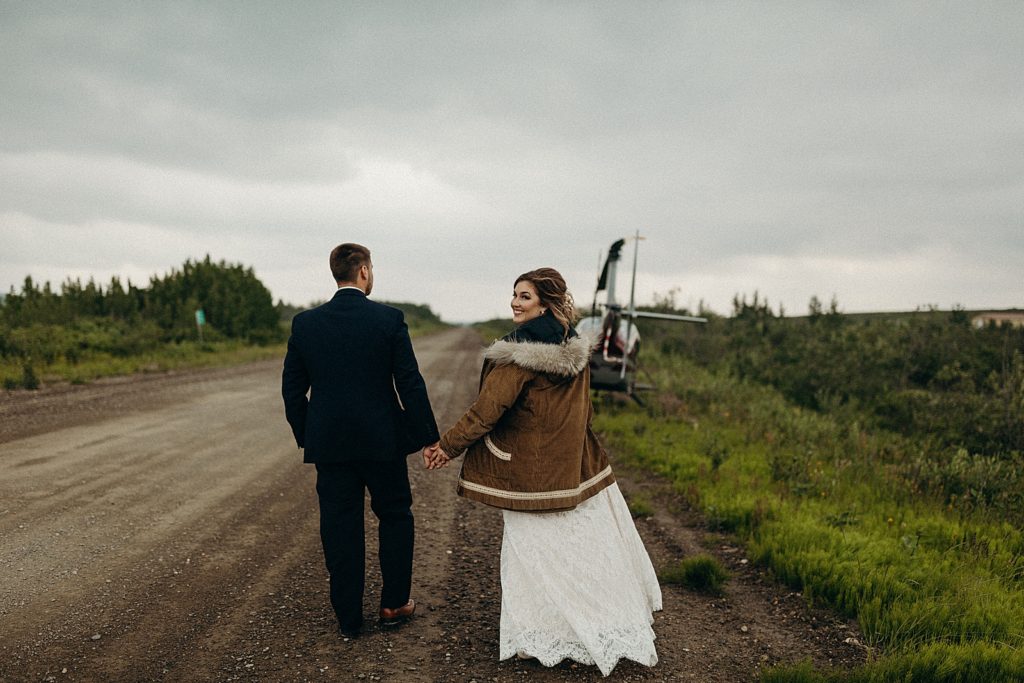 Bride and Groom holding hands about to get on Helicopter