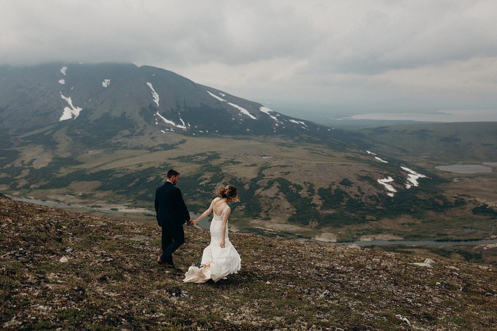 Bride and Groom holding hands and walking on the mountain together
