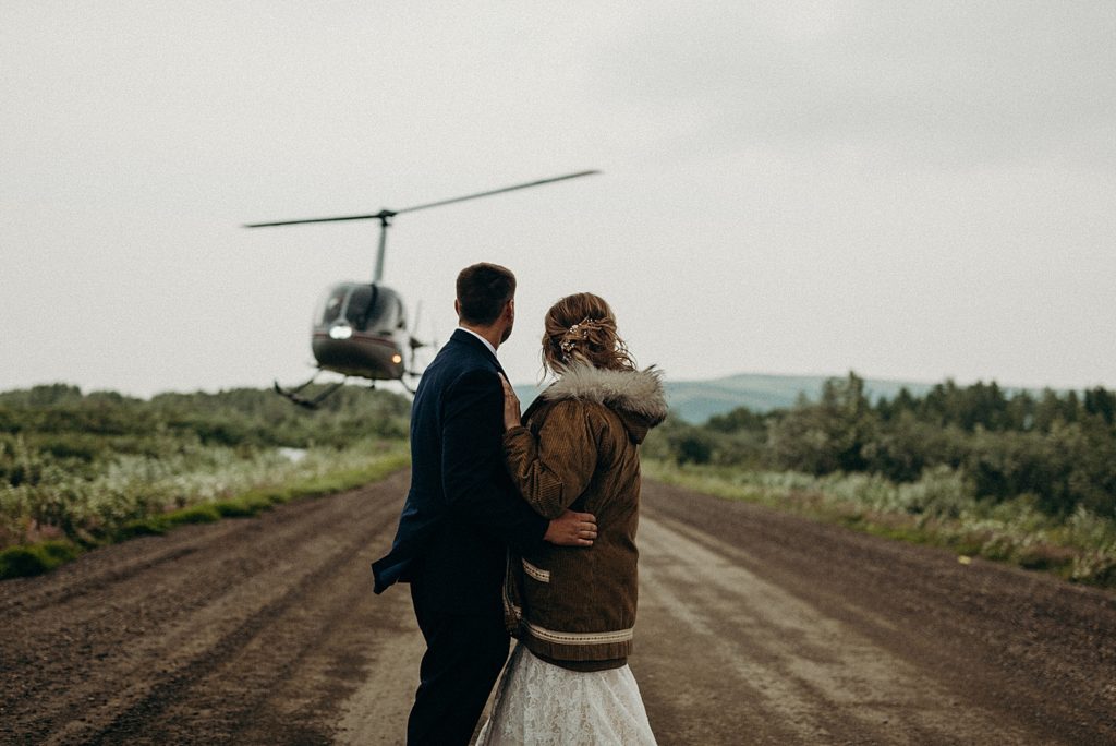 Bride and Groom holding each other and watching Helicopter take off