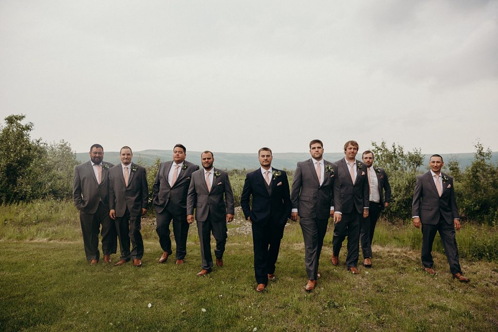 Groom and Groomsmen walking together on green grass field
