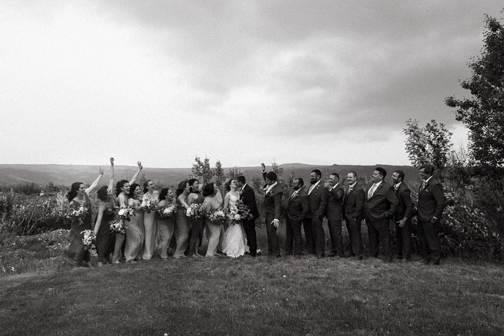 B&W Bride and Groom kissing and Bridal Party celebrating