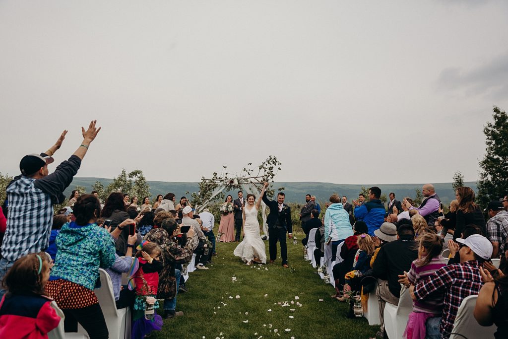 Bride and Groom raising their hands together during Ceremony exit